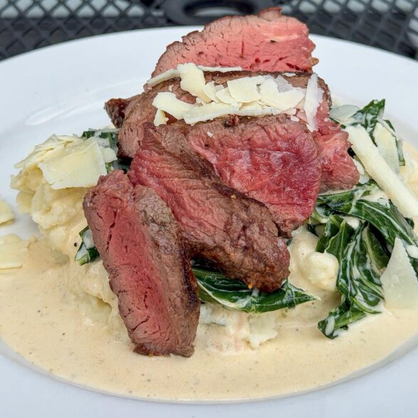 Sliced filet finished with parmesan and asiago over creamed collards and mashed potatoes